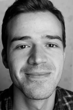 Black And White Portrait Of Handsome Smiling Man Isolated On Gray Studio Background Posing To The Camera