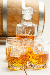 whiskey glass with ice and a carafe on the background of wooden barrels