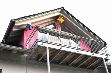 Moderner Haus-Giebel mit Stahl-Balkon. Ziegeldach und Weihnachtsstern