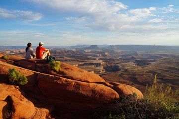 Two hikers enjoy the view form the Green River Overview, looking down into the valley carved by the Colorado and Green River. Canyonlands National Park, Utah, USA