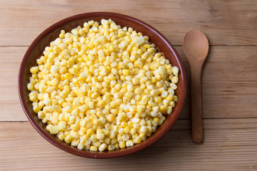 Frozen corn in a bowl with a wooden spoon