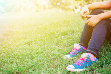 Kid sitting on the green grass in the park with copy space