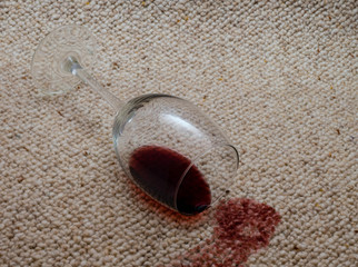 Umgekipptes Weinglas auf hellem Teppich