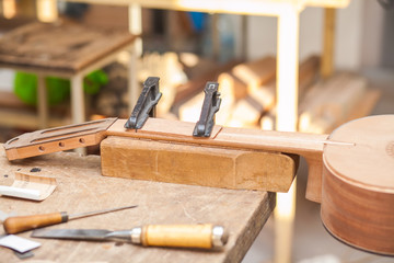 unfinished guitar on table at workshop with tools