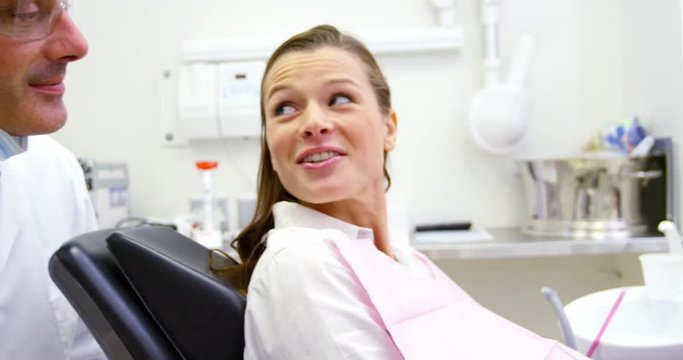 Smiling dentist talking to female patient