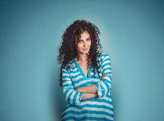 Portrait of curly young gorgeous brunette woman isolated over blue background wall.