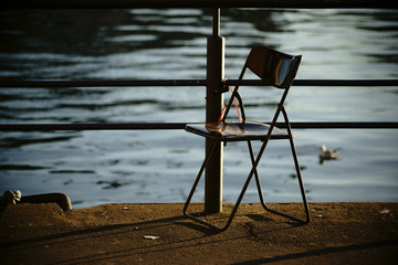 Sitzplatz Seitenansicht / Ein alter Sitzstuhl steht angekettet an der Ufern des Mains in Frankfurt