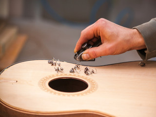 Serious professional guitar-maker working with unfinished guitar at workshop