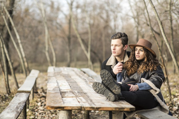 Romantic young man with a young woman on a romantic date. The guy with the girl sitting at a long wooden table. Young people in love.