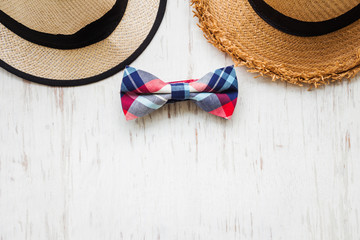 Men's accessories with brown hat and plaid bow tie on rustic wooden background 