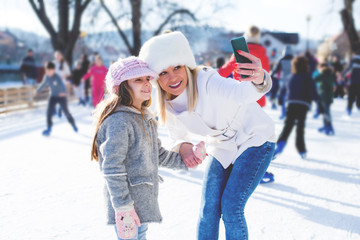 Mother and daughter taking selfy in skating ring.Colored photo