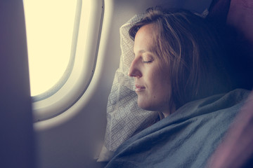 Female passenger sleeping covered with blanket.