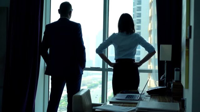Businesspeople admire view from window in office
