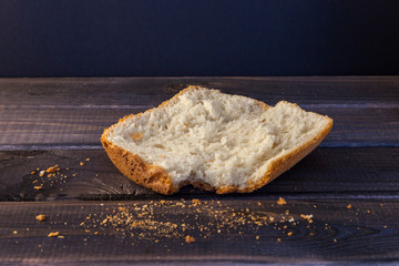 Big slice of white homemade bread on wooden table on black background.