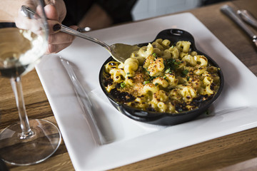 A woman takes a bite of macaroni and cheese at a restaurant.