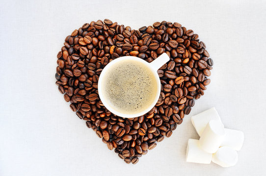 Background from coffee Valentine's Day. Coffee beans in the shape of a heart and a cup of freshly brewed coffee.