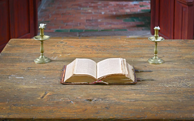 Very old open bible on table in medieval church