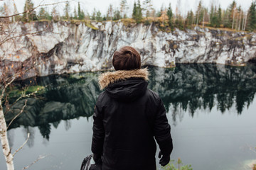 Fototapeta na wymiar Man enjoy beautiful lake view from the hilltopl and good weather in Karelia. Around the rocks.