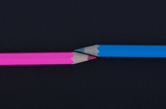 Pink and blue wooden pencils on black background.