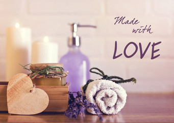Spa and wellness setting with white towels , sponge, candle, lavender and wooden heart on bricks wall background. Valentine's postcard