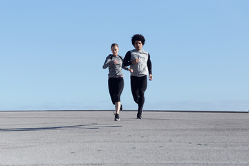 Fit and sporty couple running in the street.