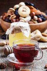 Black tea in a glass cup with honey, dried fruits and nuts, swee