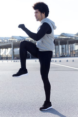 Fit and sporty young man doing stretching in city.