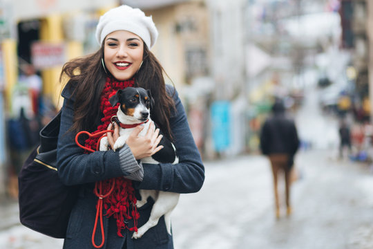 Beautiful young brunette woman enjoying city street outdoor together with her gorgeous Jack Russell terrier. 