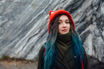 Portrait of a beautiful hipster girl on the background  the rocky cliffs. Dyed hair, blue, long.