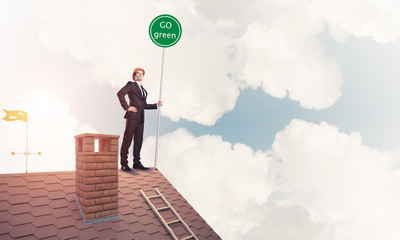 Businessman in suit on house top with ecology concept signboard.