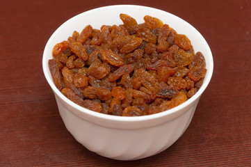 Raisins in white bowl or cup. Dried sweet berries.