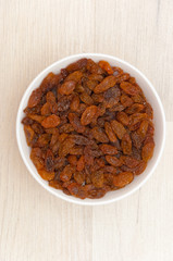 Raisins in white bowl or cup. Dried sweet berries.