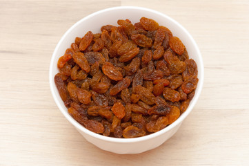 Raisins in white bowl or cup. Dried sweet berries.