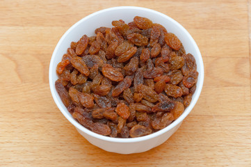 Raisins in white bowl or cup. Dried sweet berries.