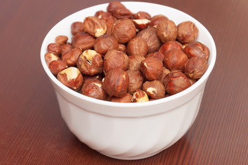 Hazelnuts in white bowl or cup  at wooden background. Healthy fo