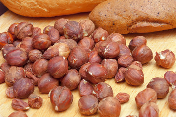 Hazelnuts and bread on wooden desk.
