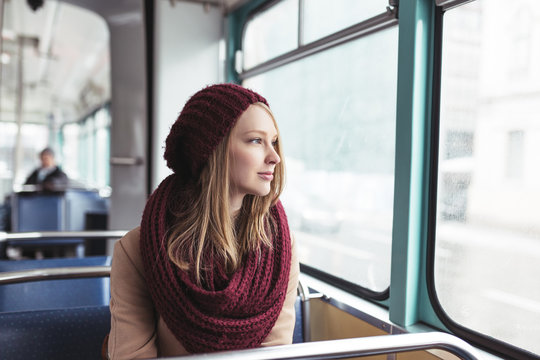 Beautiful young woman sitting in tram and looking through window. 