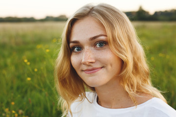 A portrait of beautiful young blue-eyed girl with light hair having charming smile and dimple on...