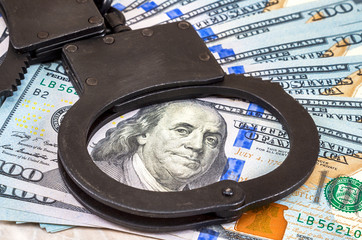 Steel police handcuffs lying on the background of american dolla