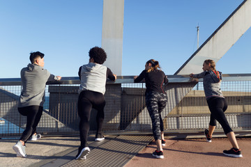 Portrait of running people doing stretching in the city.