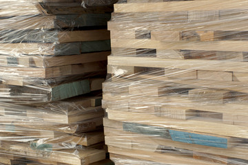 Wooden planks stacked in rows wrapped in plastic foil