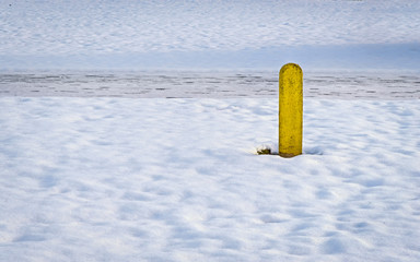 One yellow pole in the snow during winter