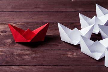 Business leadership concept with white and color paper boats on 