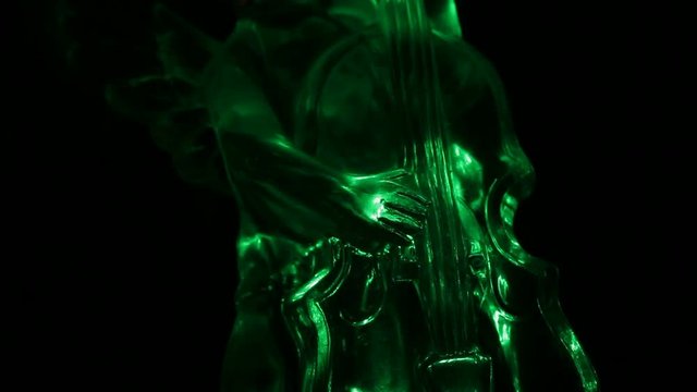 Little angel playing the violin. Light shines in the darkness