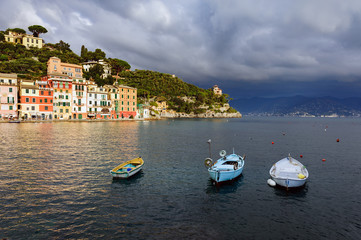 Fototapeta na wymiar Stormy sky and small boats in sea bay of Portofino town. Portofino is small fishing town in Liguria district in Italy.