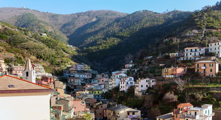Fototapeta premium Village of Riomaggiore town with houses, located between mountains at Cinque Terre national park, Italy