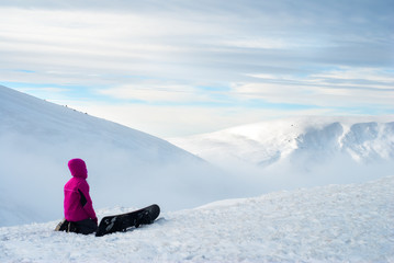 Fototapeta na wymiar girl sitting with a snowboard on top of mountain
