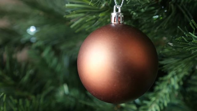Shallow DOF Christmas Eve and day tree with beautiful matte ornament 4K 2160p 30fps UltraHD footage - White lights surrounding bronze color bauble close-up 3840X2160 UHD video 
