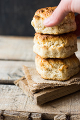 Stack of homemade scones with woman's hand on burlap on vintage wood table, black wall, rustic kitchen interior, minimalistic, kinfolk