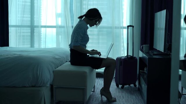 Businesswoman working on laptop sitting in hotel room 
